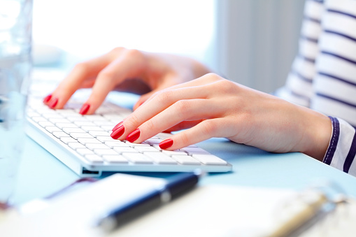 Close-up of woman's hands are typing on a computer keyboard. Young businesswoman sitting at office and working online.