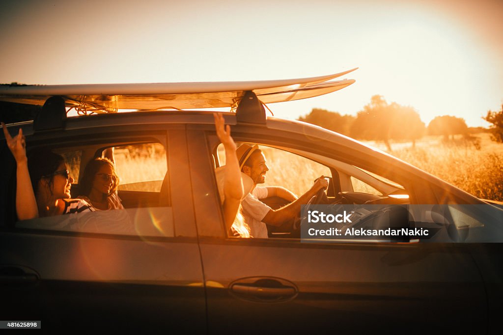 Surfer's lifestyle Group of surfers driving in the car, getting ready for their summer trip, while surfboards are packed on the roof Car Stock Photo