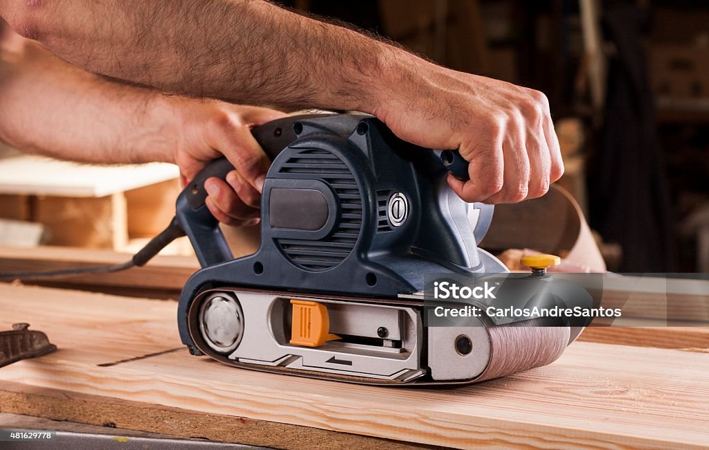 carpenter works with belt sander in carpentry 2015 Stock Photo