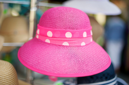 Pink women`s straw hat with pattern at outdoors shop.