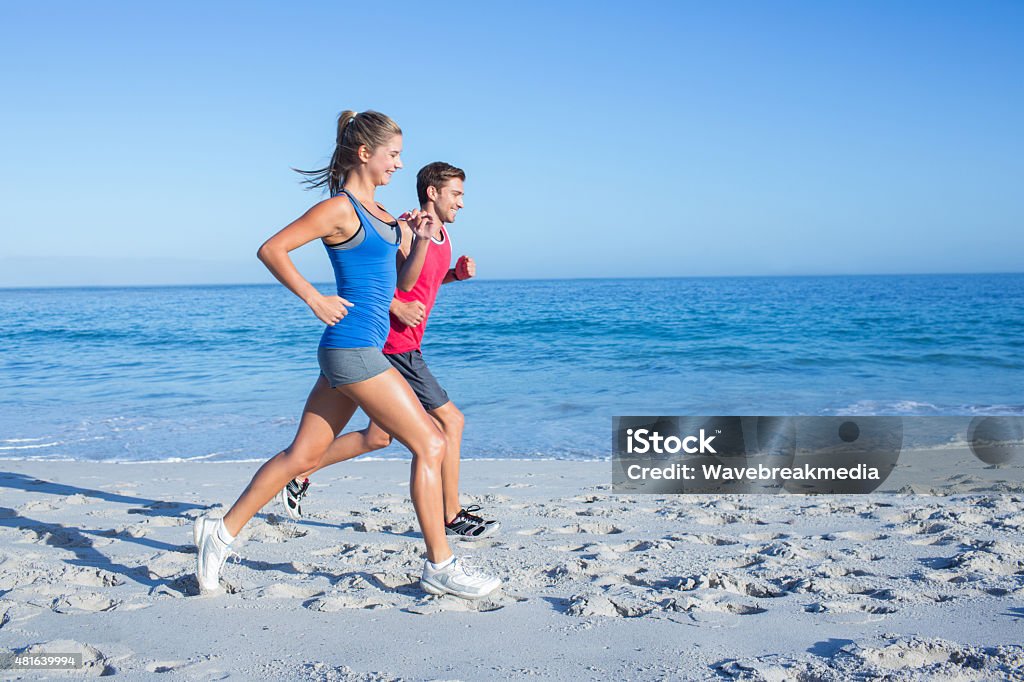 Happy couple running together beside the water Happy couple running together beside the water at the beach 20-24 Years Stock Photo