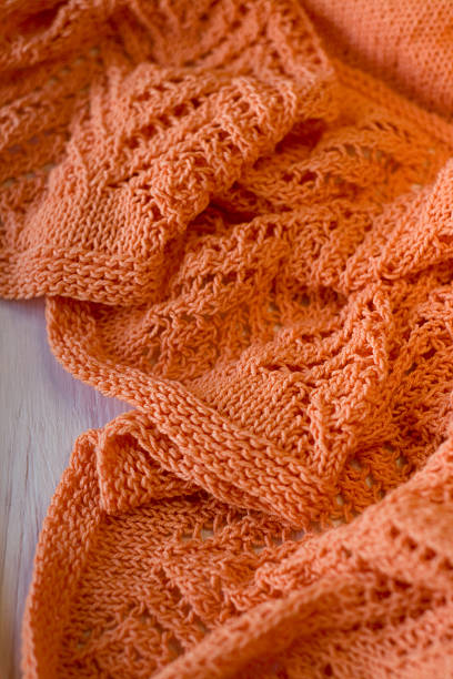 istock Bright orange Knitted plaid on a white wooden background 481643506