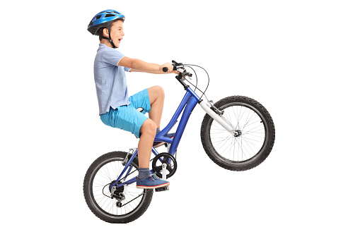 Niño haciendo un sobre ruedas traseras en una pequeña azul bicicleta photo