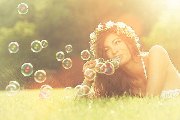 istock Young woman having fun and blowing bubbles outdoors 481647395