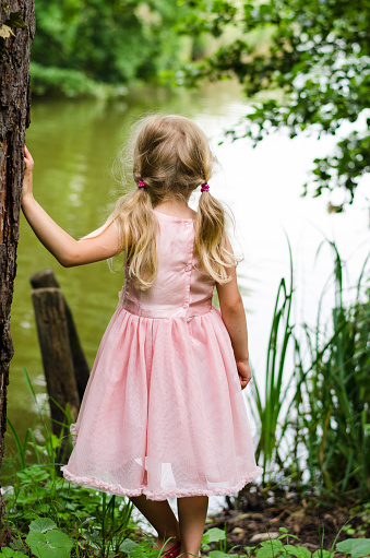 little blond girl looking to the pond