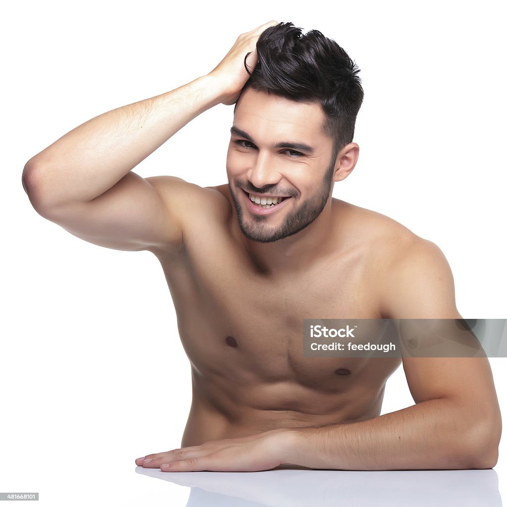 young laughing man is posing for the camera young laughing man is posing for the camera while passing his hand through his hair Handsome People Stock Photo