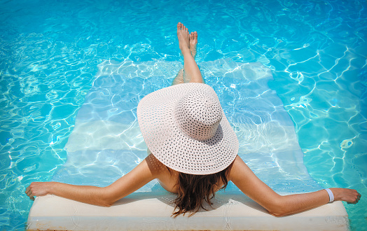 young woman in white hat resting in pool.