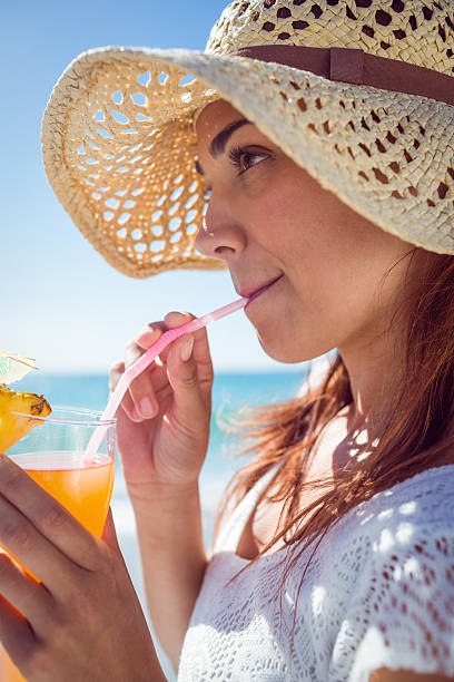 istock Brunette wearing straw hat and drinking a cocktail 481675242