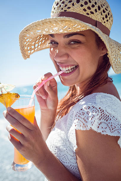 istock Smiling brunette wearing straw hat and drinking a cocktail 481675244