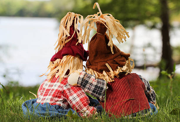 vue arrière de l'épouvantail assis près du lac - child autumn scarecrow decoration photos et images de collection