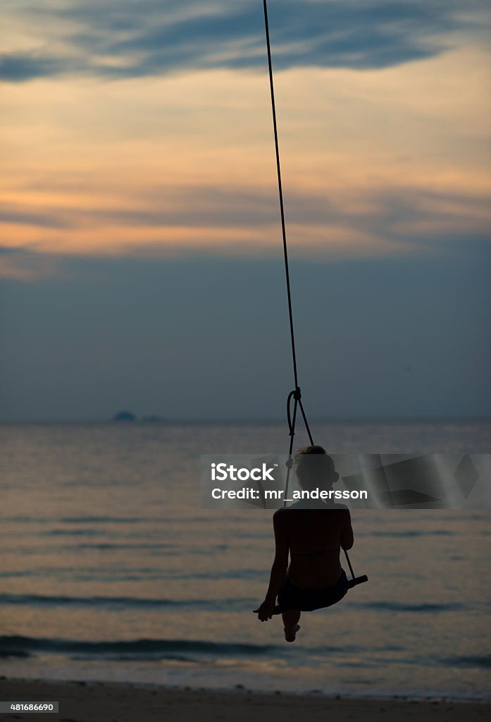 Woman in Swing at Tropical Sunset Gentle beach sunset swinging at Tioman Island, Malaysia 2015 Stock Photo