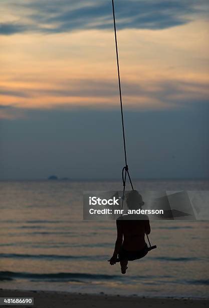 Woman In Swing At Tropical Sunset Stock Photo - Download Image Now - 2015, Adult, Affectionate