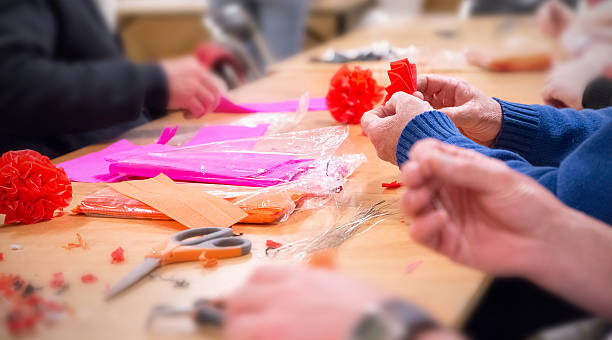 Volunteers manufacture colored crepe paper decorations on table