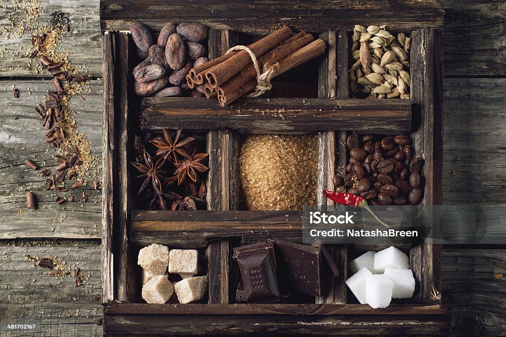 Coffe, chocolate, sugar and spices Top view on old wooden box with set of coffee and cocoa beans, sugar cubes, dark chocolate, cinnamon and anise over wooden background Backgrounds Stock Photo