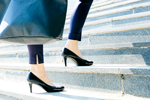 During morning rush businesswoman legs in motion are focused on ascending office stairs.