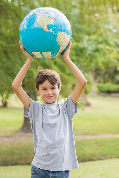 istock Smiling boy holding an earth globe in the park 481714484