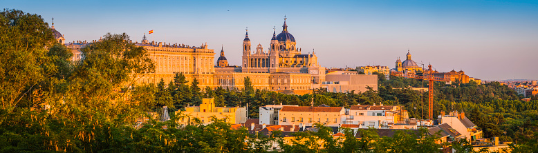 Golden light of sunset illuminating the ornate domes and spires of the Almundena Cathedral and classical facade of the Palacio Real across the rooftops of central Madrid, Spain's vibrant capital city. ProPhoto RGB profile for maximum color fidelity and gamut.