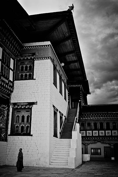 The Tashi Chho Dzong Fortress, Thimpu, Bhutan Thimpu, Bhutan - October 25, 2014: A Buddhist monk stands in the courtyard of the Tashi Chho Dzong Fortress, Thimpu, Bhutan black and white travel travel destinations monk stock pictures, royalty-free photos & images