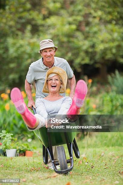 Happy Senior Couple Playing With A Wheelbarrow Stock Photo - Download Image Now - Fun, Senior Adult, Senior Couple
