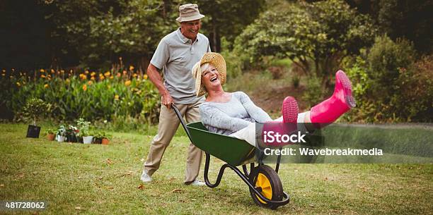 Happy Senior Couple Playing With A Wheelbarrow Stock Photo - Download Image Now - Gardening, Senior Adult, Fun