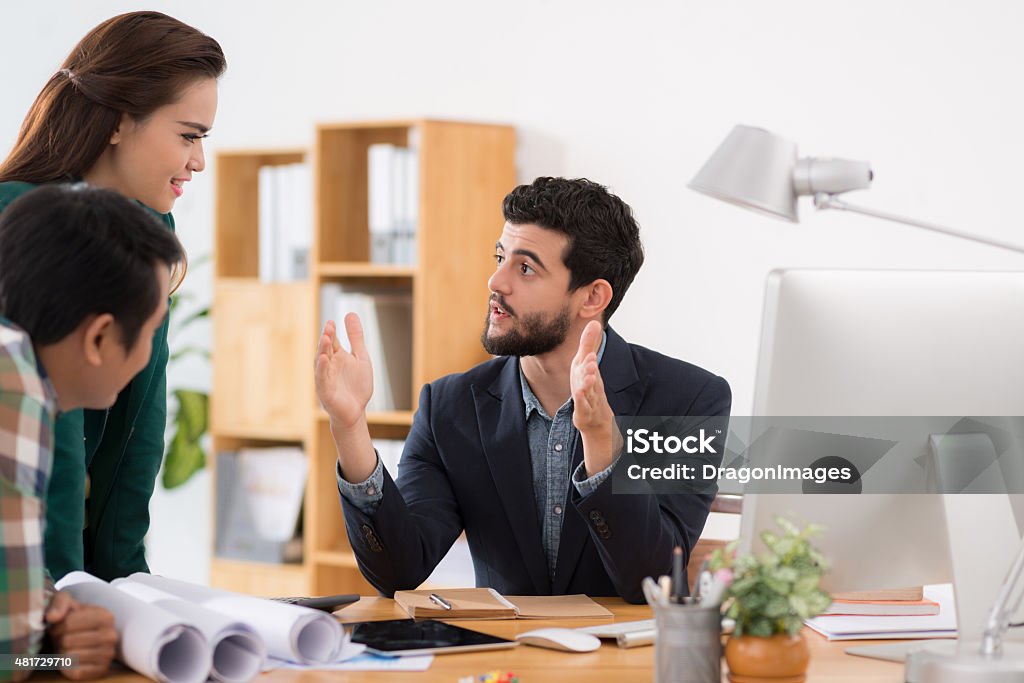 Explaining business strategy Handsome young businessman explaining business strategy to his colleagues 2015 Stock Photo