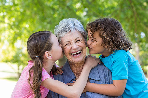 familia sonriendo y beso en un parque - grandchild fotografías e imágenes de stock