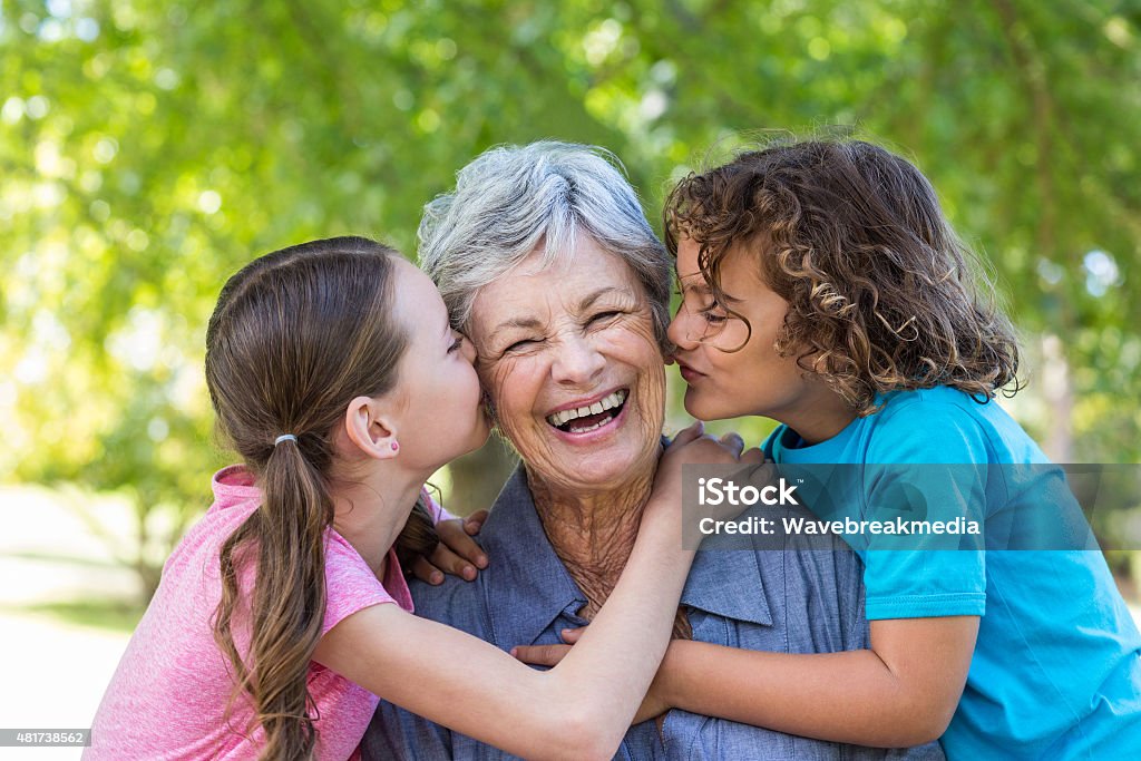 Extended family smiling and kissing in a park Extended family smiling and kissing in a park on a sunny day Grandmother Stock Photo