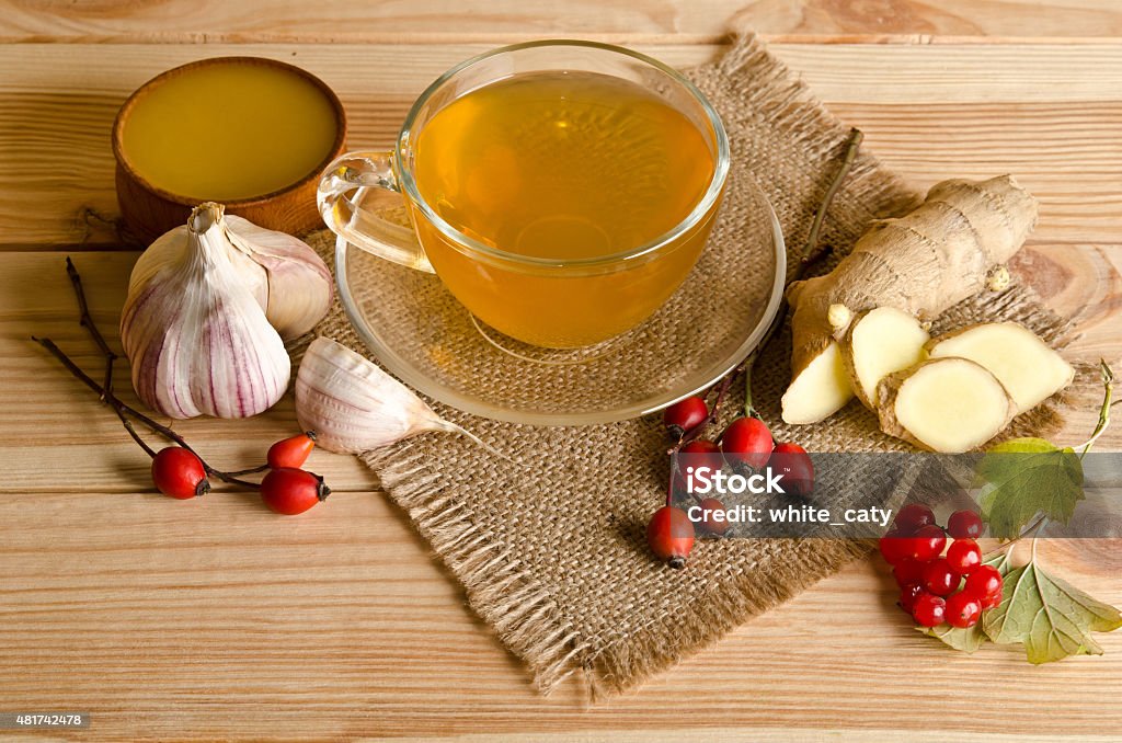 Cup of tea,slices of ginger,honey,rosehip berries and viburnum Cup of tea,slices of ginger,honey,rosehip berries and viburnum on a wooden table 2015 Stock Photo