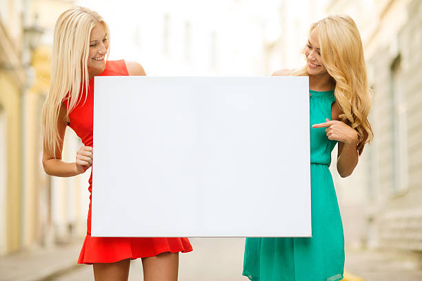 istock two happy blonde women with blank white board 481742624