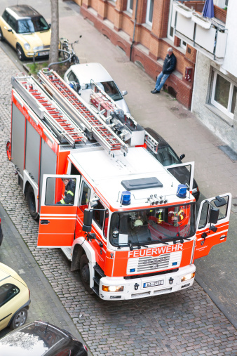 Wiesbaden, Germany - March 12, 2014: German fire truck, arriving at place of action in the city center of Wiesbaden. View from above. In the background some passersby