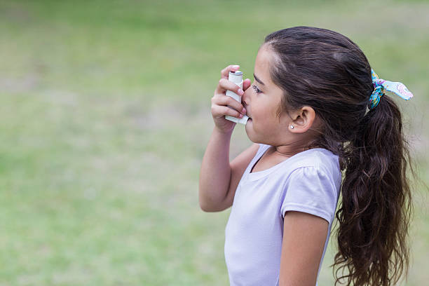 niña utilizando su inhalador - inhalador de asma fotografías e imágenes de stock