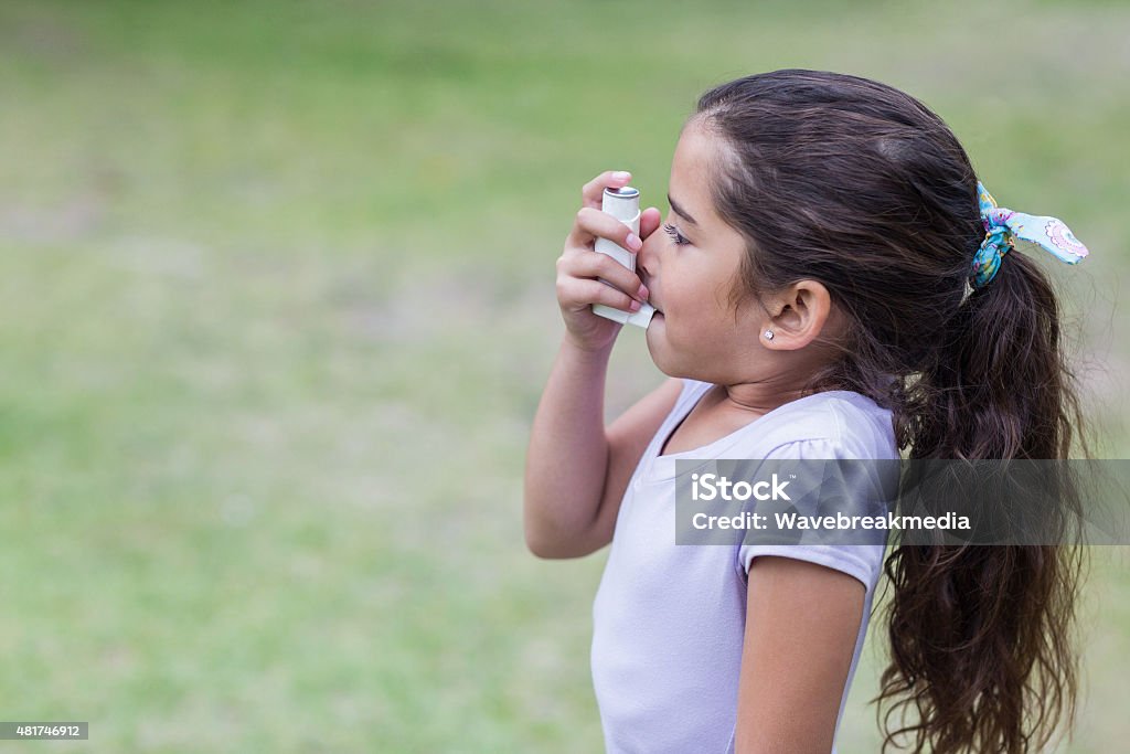 Little girl using his inhaler Little girl using his inhaler on a sunny day Asthmatic Stock Photo