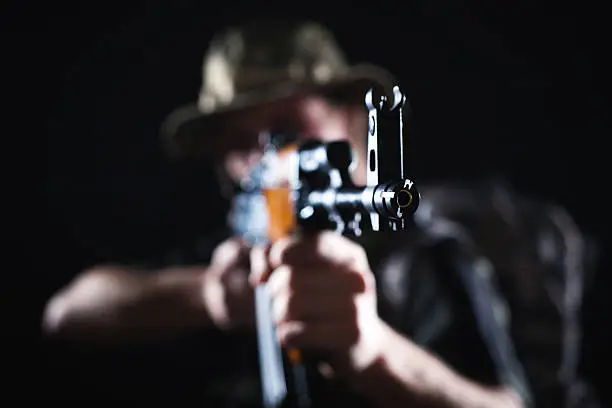 Focus on Kalashnikov rifle being held by blurred soldier in combat.