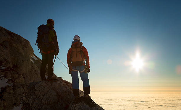 les grimpeurs debout sur les rochers et la recherche au coucher du soleil, la vue de dos - mountain rock sun european alps photos et images de collection