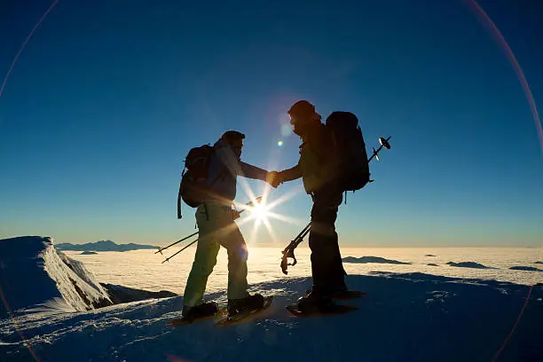 Julian Alps, Triglav National Park, Two hikers standing on snow covered landscape and shaking hands with each other.