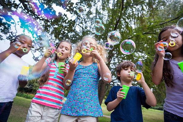 istock Little friends blowing bubbles in park 481761080