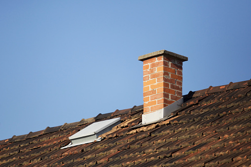 several chimneys on the gabled roof of an old apartment building