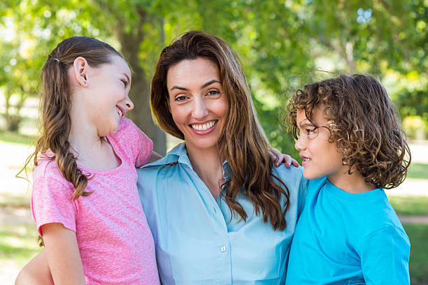 istock mother and children smiling in a park 481772192