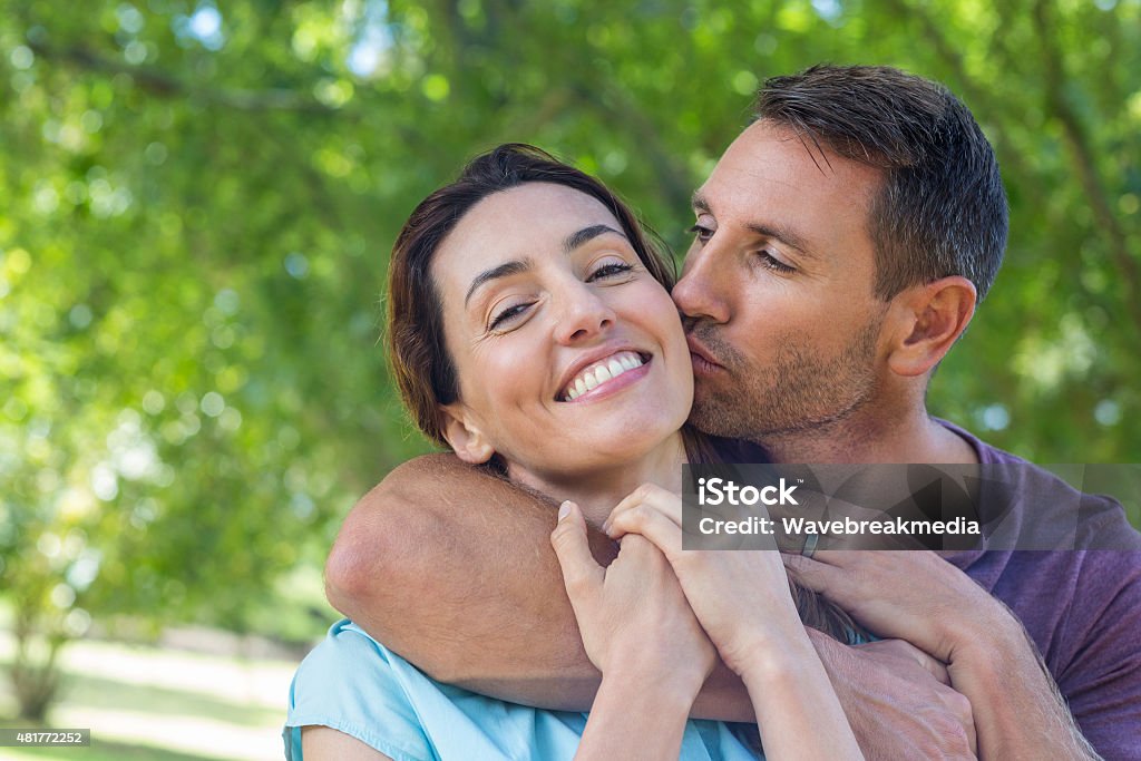 Happy couple smiling at camera in park Happy couple smiling at camera in park on a sunny day 2015 Stock Photo