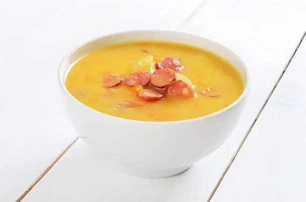 Pea soup in bowl on white wooden table