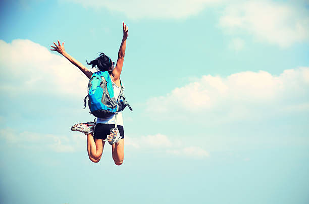 istock cheering woman hiker jumping against blue sky 481773656
