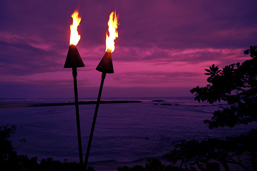 This is a photograph of two tiki torches at a resort on the North Shore in Hawaii. The focus is on the torches and falls off in the background.
