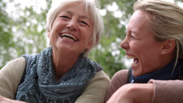 Mother and adult daughter laughing outdoors, slow motion