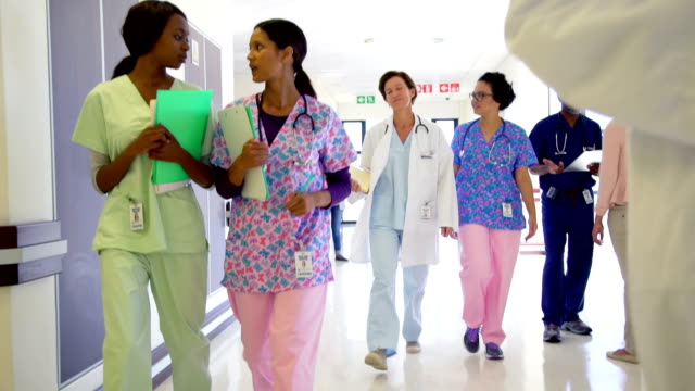Doctors and nurses talking and walking in hospital corridor