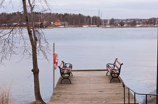 Dock with benches and lifebuoy near lake stock photo