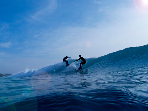 Bali, Indonesia - June 6, 2012: Silhouettes of two surfers on the wave