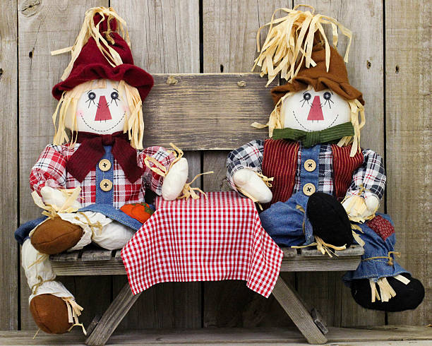 istock Scarecrows sitting at table by blank wood sign 481790232