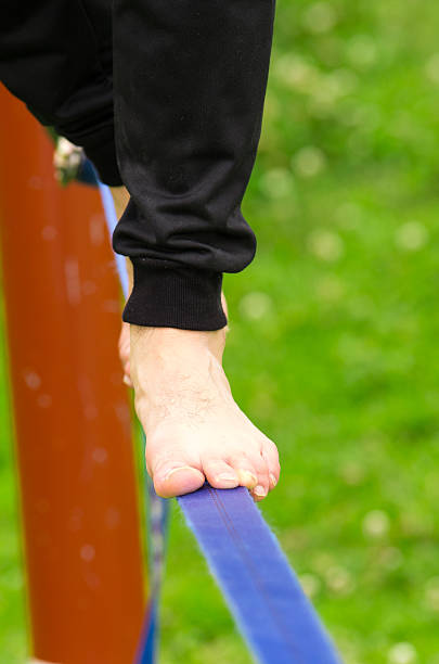 istock Closeup man feet walking on slackline and grassy background 481793844