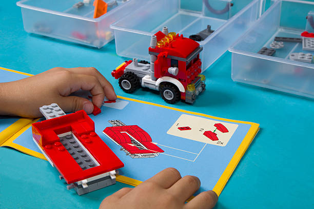 Asian Learns To Build Lego Following Instruction Manual Stock Photo - Download Image Now - iStock