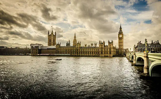 Houses of Parliament and Westminster Palace, with the worldwide known Big Ben clock tower in London seen from across Thames river.